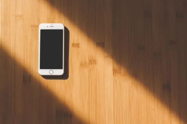 iPhone blanco sobre una mesa de madera con luz natural